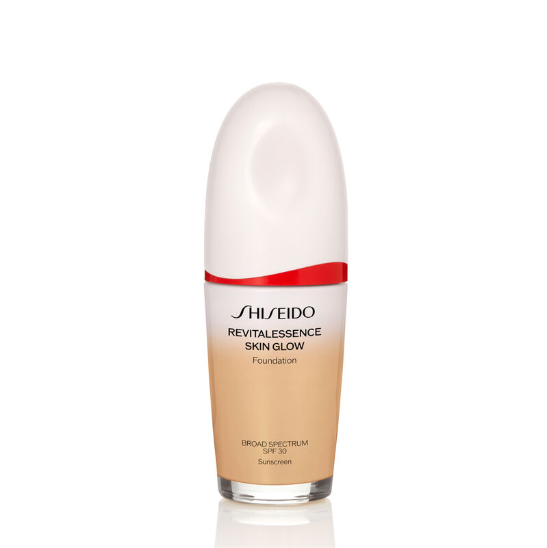 An oval-shaped bottle of Shiseido Revitalessence Skin Glow Foundation SPF 30 in shade 320 Pine. The label on the bottle is white with a red accent. The text on the label reads the product&rsquo;s title, and its sunscreen protection.