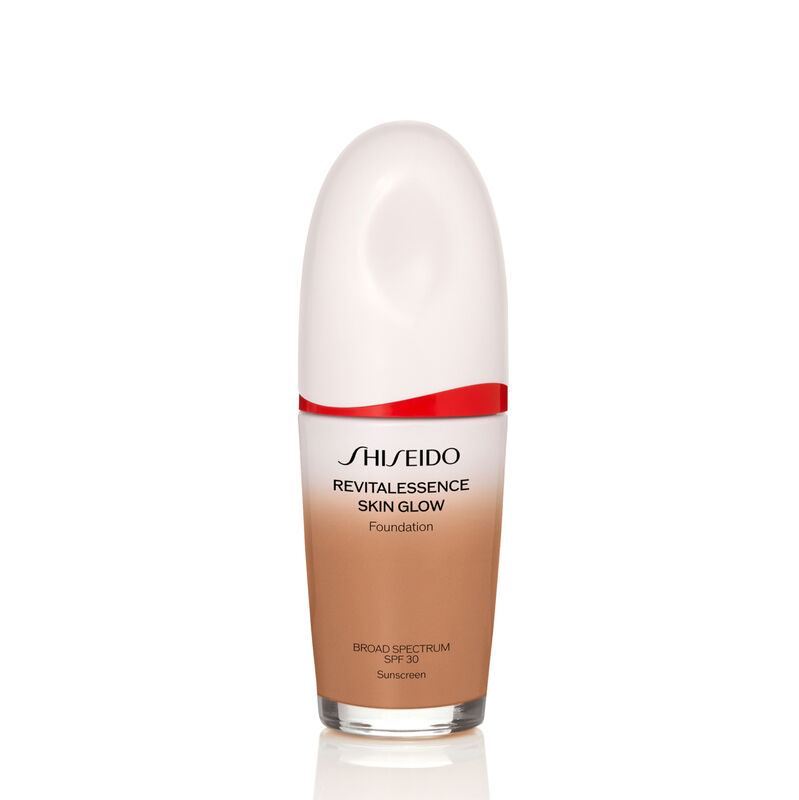 An  oval-shaped bottle of Shiseido Revitalessence Skin Glow Foundation SPF 30 in shade 410 Sunstone. The label on the bottle is white with a red accent. The text on the label reads the product&rsquo;s title, and its sunscreen protection.