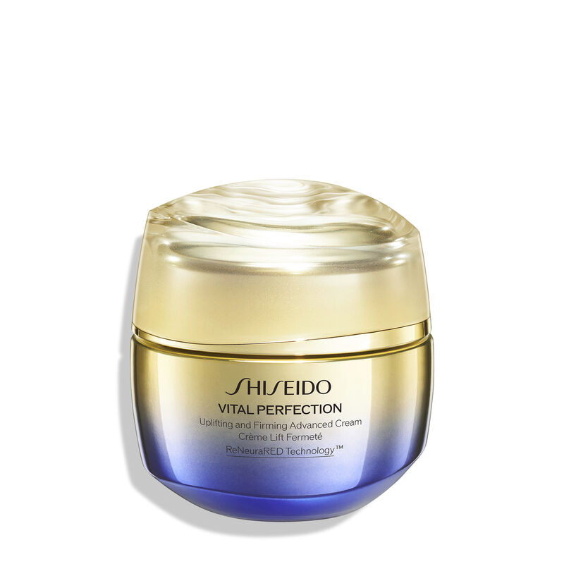 Un frasco redondo de color dorado y morado de la crema Shiseido Vital Perfection Uplifting and Firming Advanced Cream. El frasco cerrado lleva el logotipo de Shiseido, el nombre del producto y las palabras "ReNeuraRED Technology".
