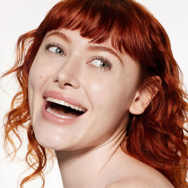 "A headshot of a model wearing the Shiseido Revitalessence Skin Glow Foundation SPF 30 in shade 110 Alabaster. The models&rsquo; skin appears more smooth and glowy with the foundation's medium-coverage finish. "