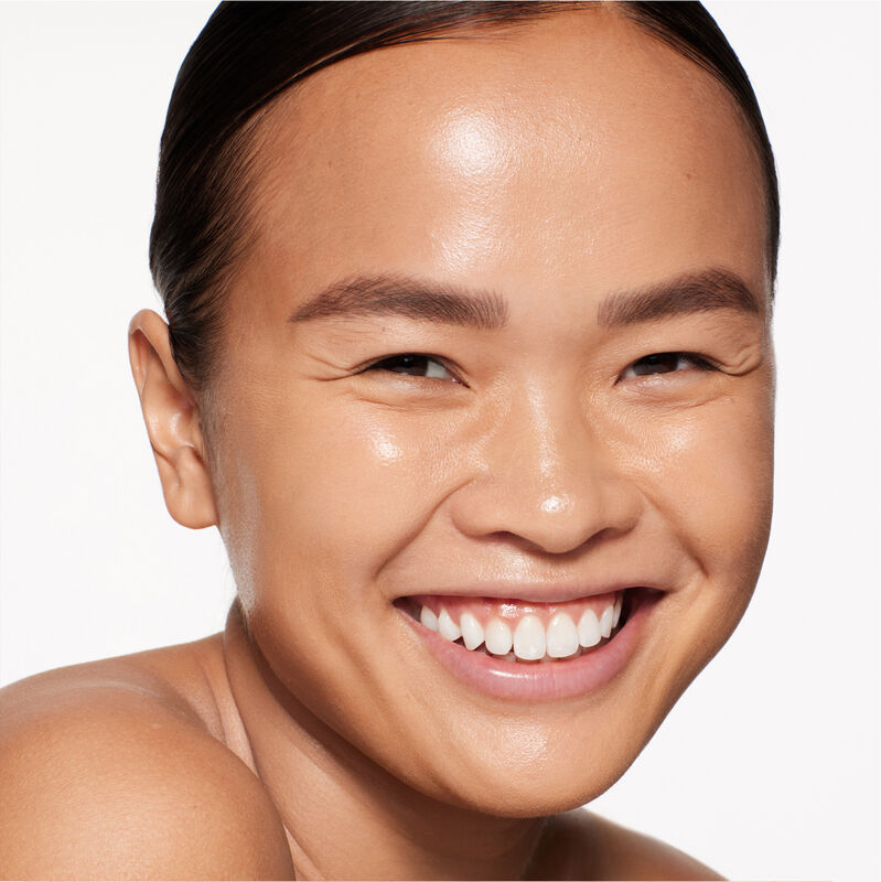 "A headshot of a model wearing the Shiseido Revitalessence Skin Glow Foundation SPF 30 in shade 350 Maple. The models&rsquo; skin appears more smooth and glowy with the foundation's medium-coverage finish.  "