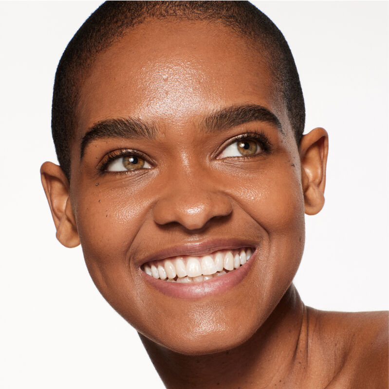 "A headshot of a model wearing the Shiseido Revitalessence Skin Glow Foundation SPF 30 in shade 440 Amber. The models&rsquo; skin appears more smooth and glowy with the foundation's medium-coverage finish.  "