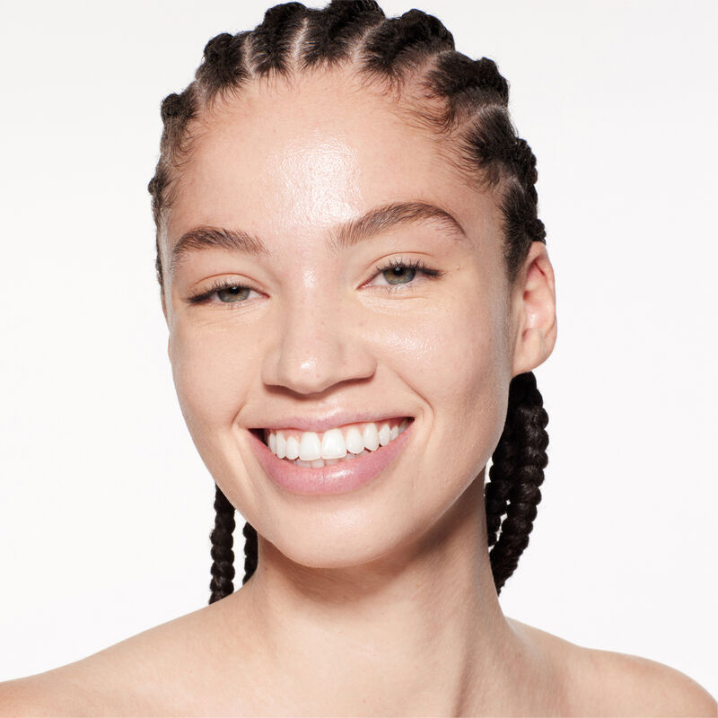 A headshot of a model wearing the Shiseido Revitalessence Skin Glow Foundation SPF 30 in shade 220 Linen. The models&rsquo; skin appears more smooth and glowy with the foundation's medium-coverage finish. 