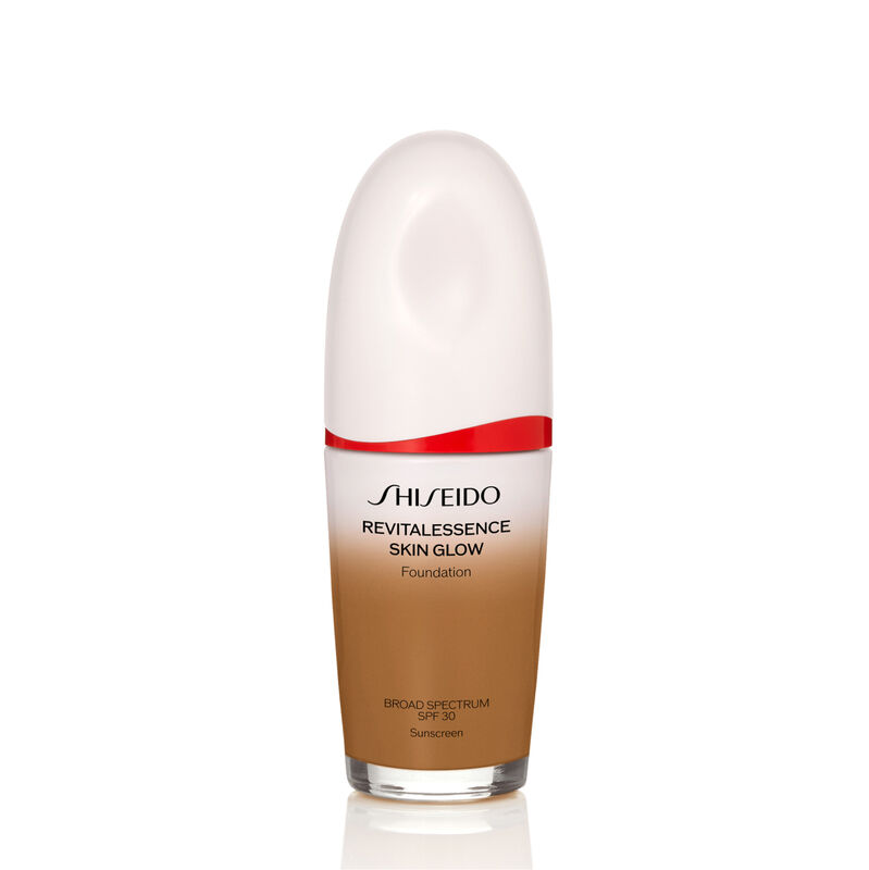 "An oval-shaped bottle of Shiseido Revitalessence Skin Glow Foundation SPF 30 in shade 440 Amber. The label on the bottle is white with a red accent. The text on the label reads the product&rsquo;s title, and its sunscreen protection. "
